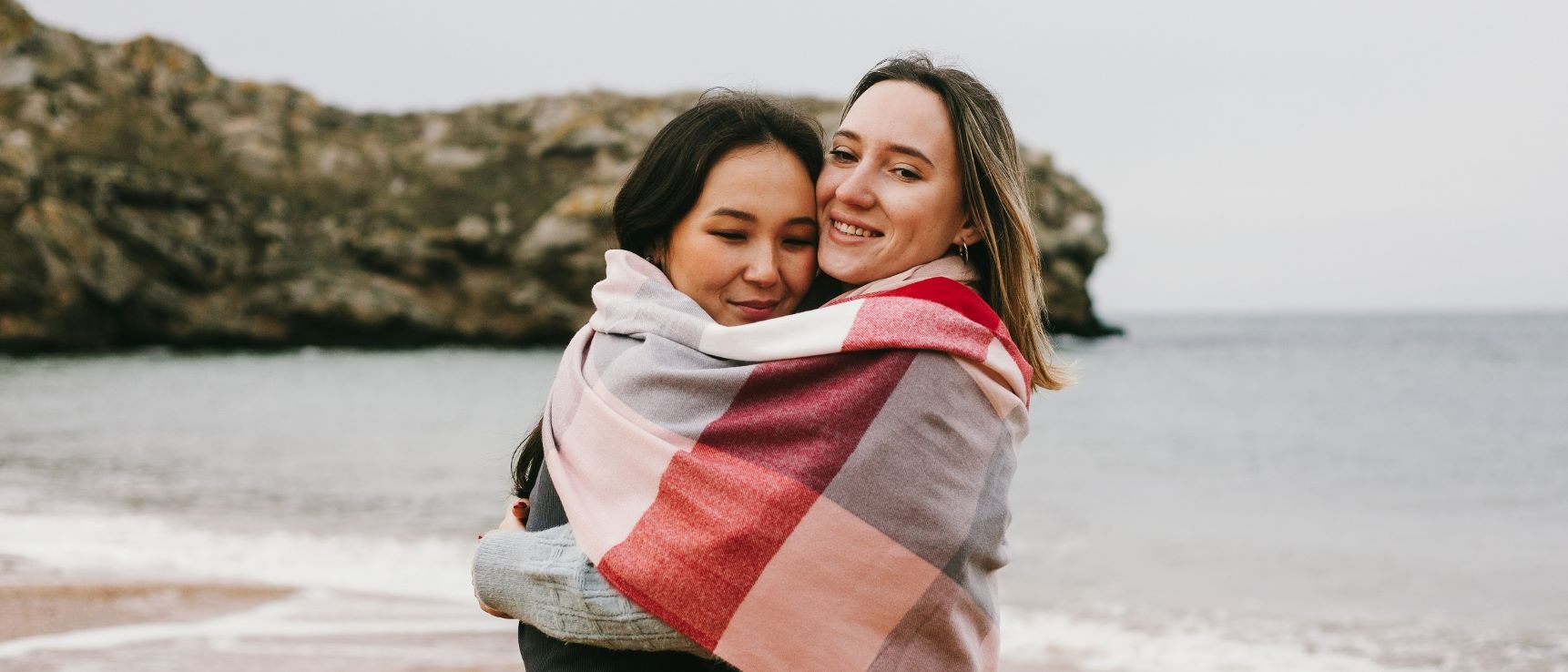 Two women hug on a beach