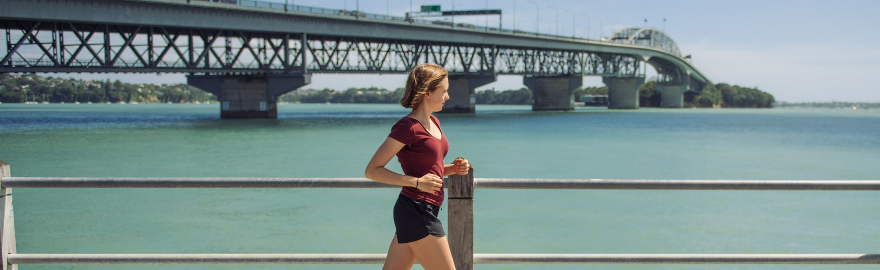 Lady running in front of Auckland Harbour
