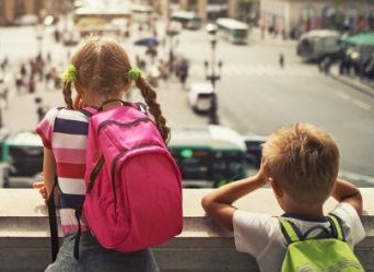 Two children looking at the street from a car