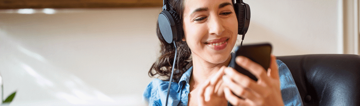 Woman listening to music with headphones connected to her phone