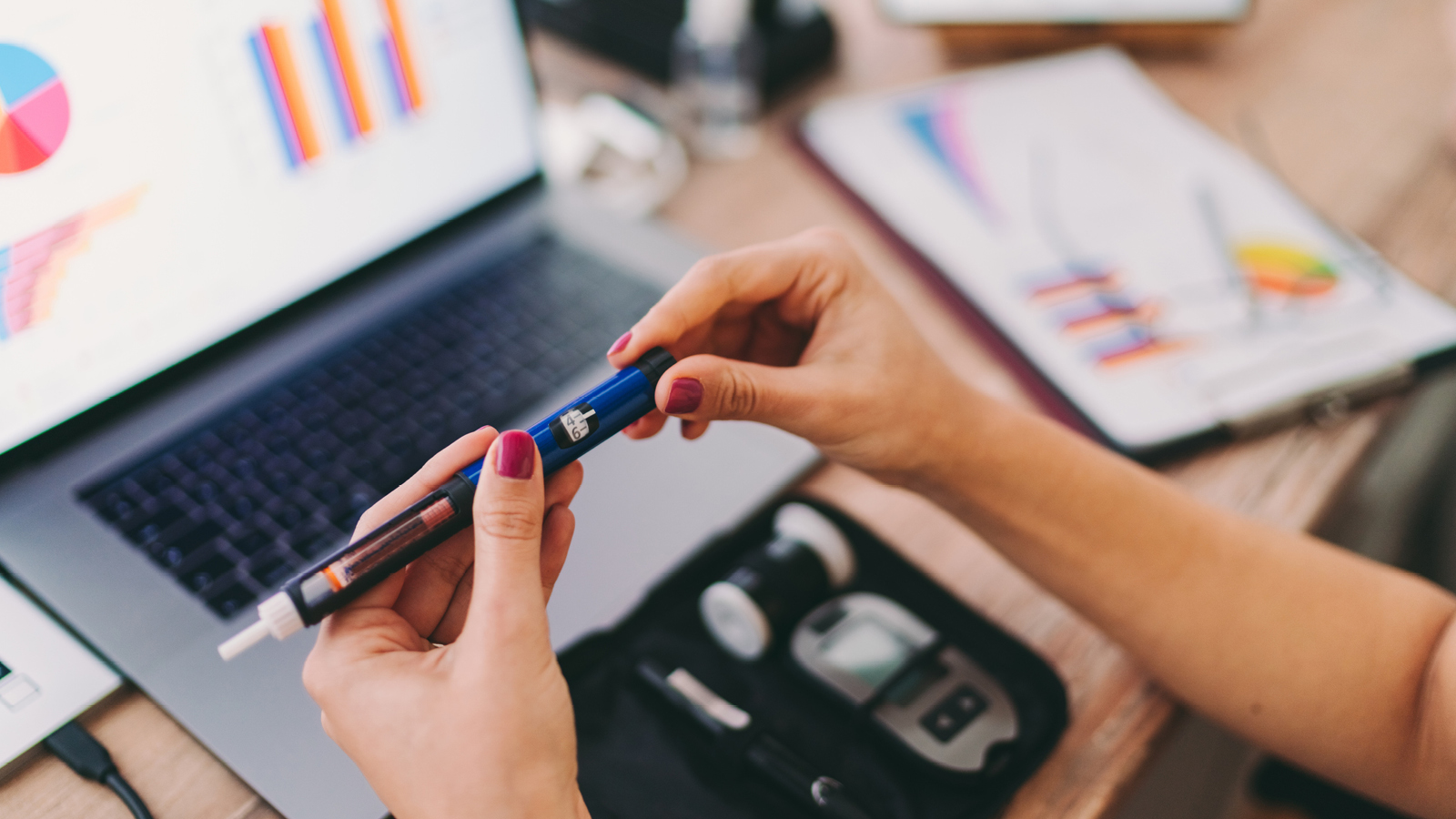 A woman holds an insulin syringe at her desk 