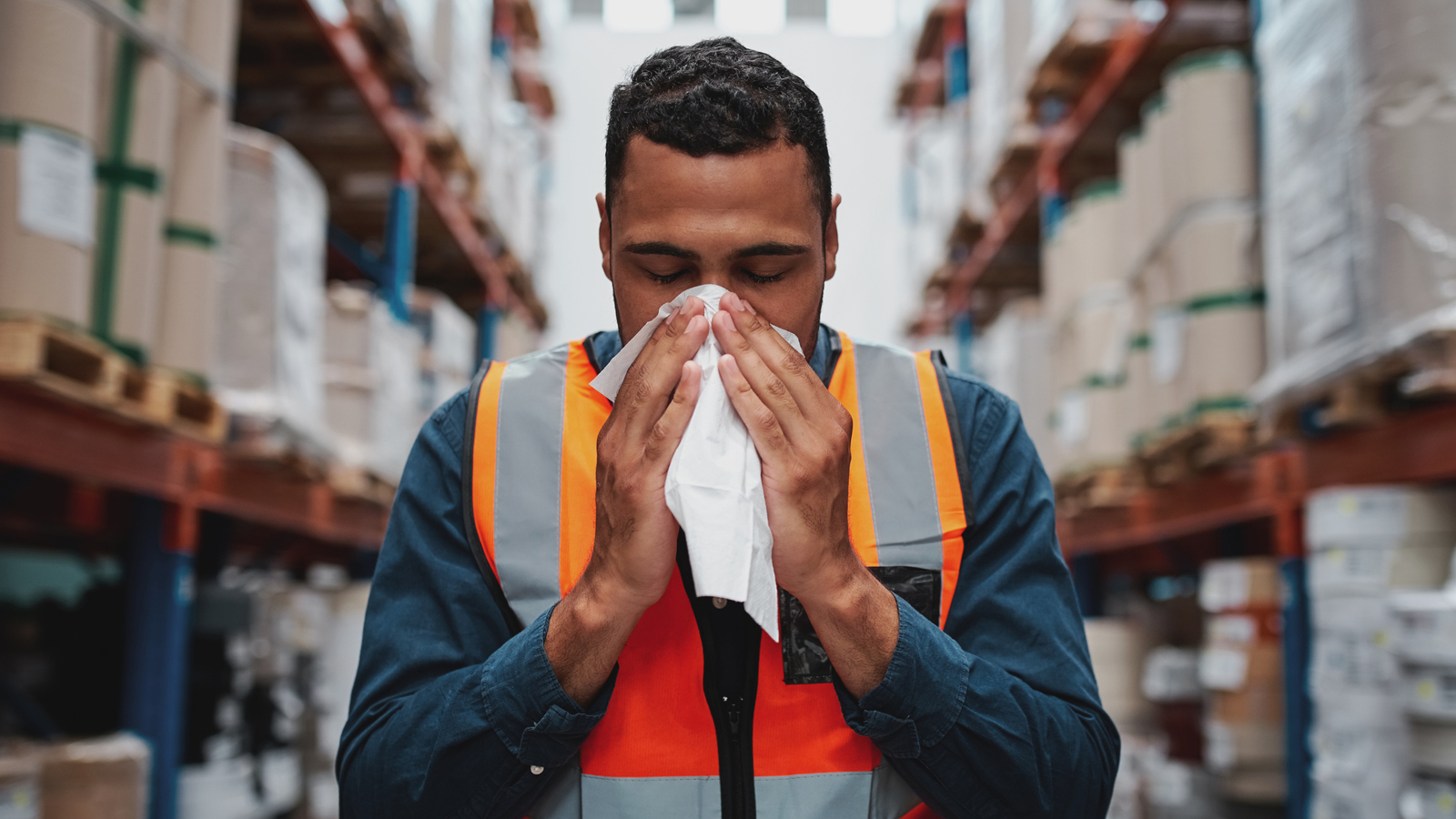 A man blows his nose into a tissue