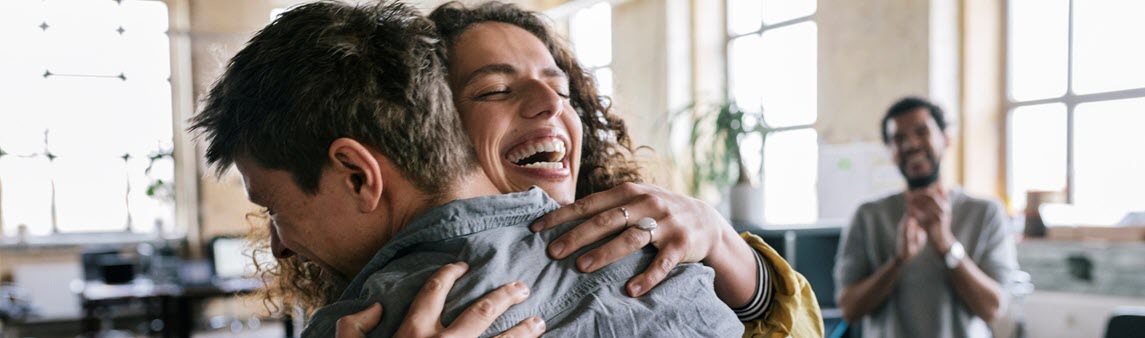 A woman hugs and man while smiling