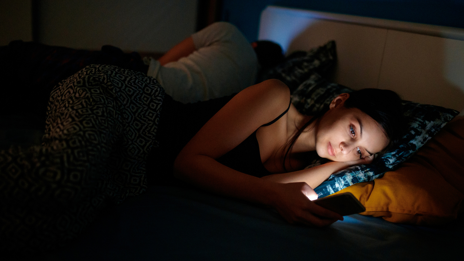 A woman looks at her phone in bed