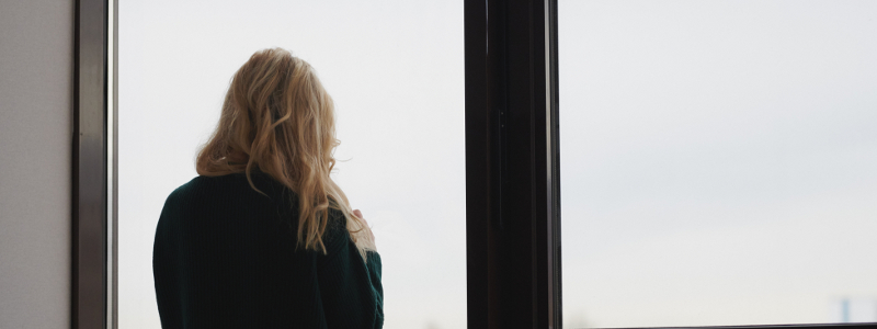 A woman looks out of a window alone