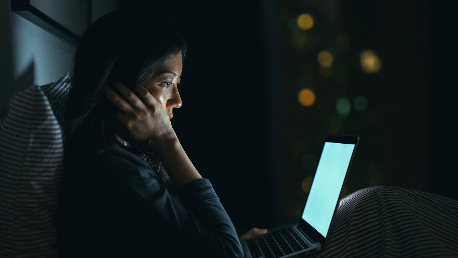 A woman in bed at night while on her laptop