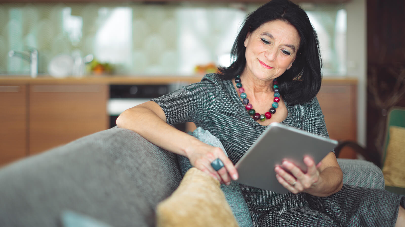 A woman reads a tablet while at home