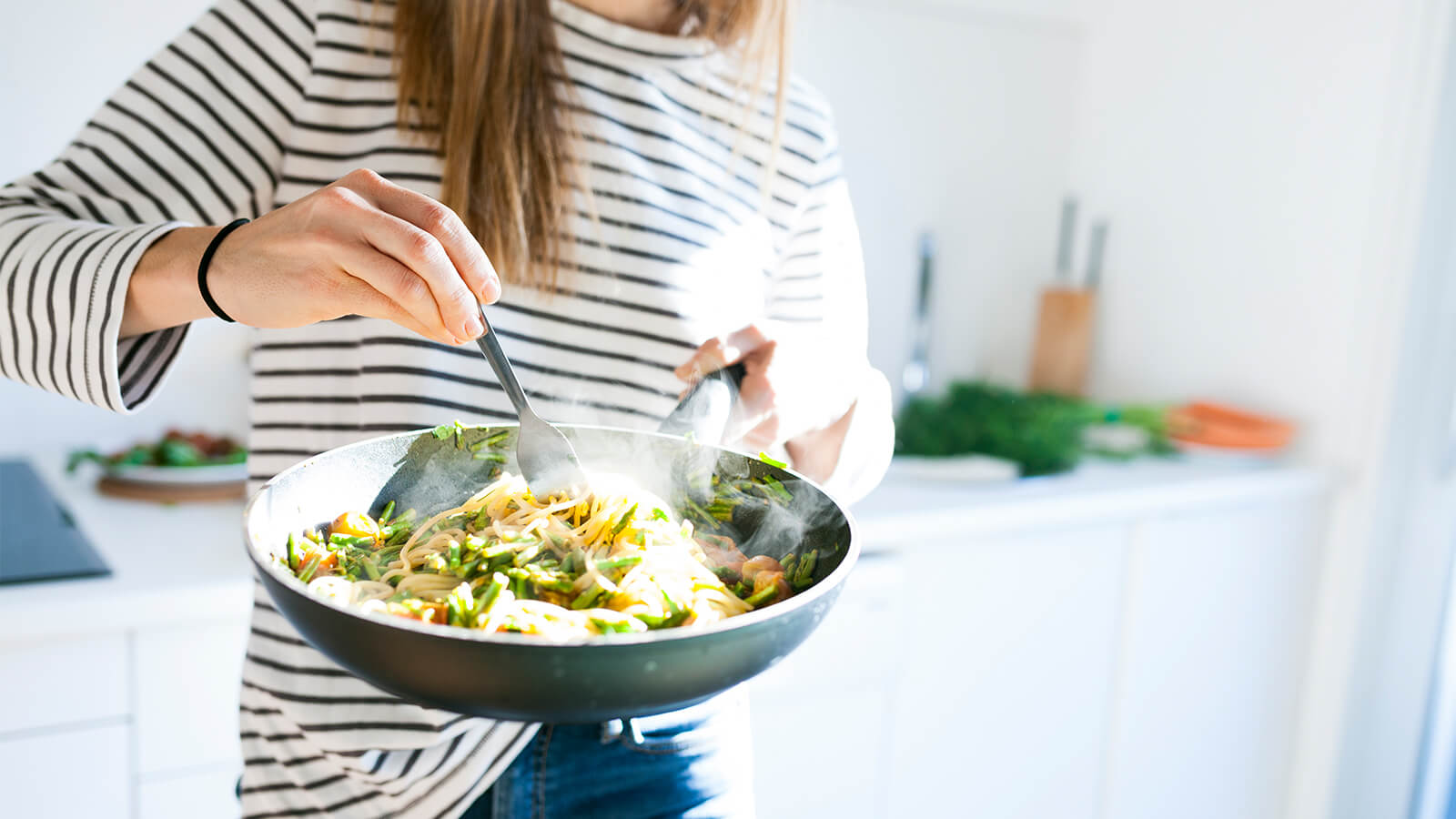 A woman cooks a stir fry in a pan