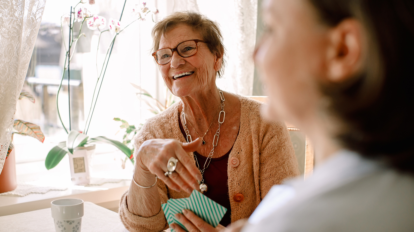 An elderly woman laughs while playing cards