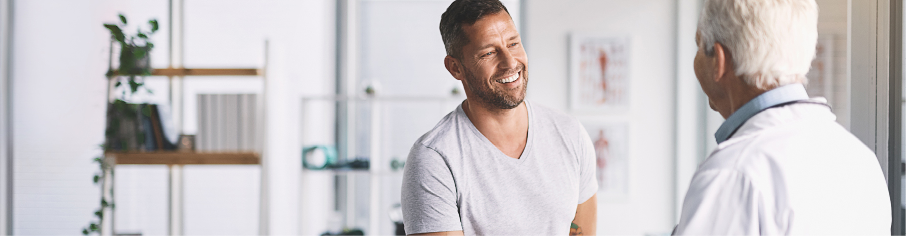 A man smiles while talking to a doctor