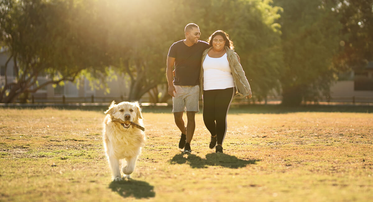 A couple walking their dog in the park