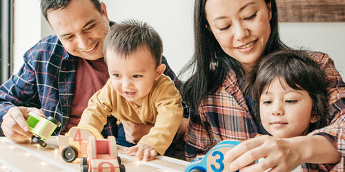 A family playing with wooden toy cars