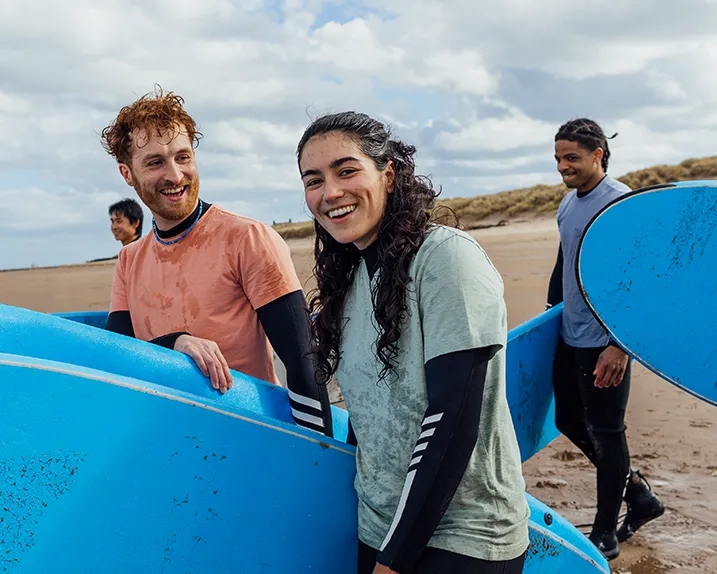 A group of friends carrying their surf boards