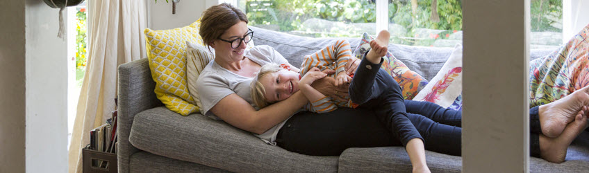 A mother and child laughing and hugging on their couch