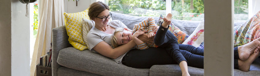 Oh hold members A mother and child laughing and hugging on their couch