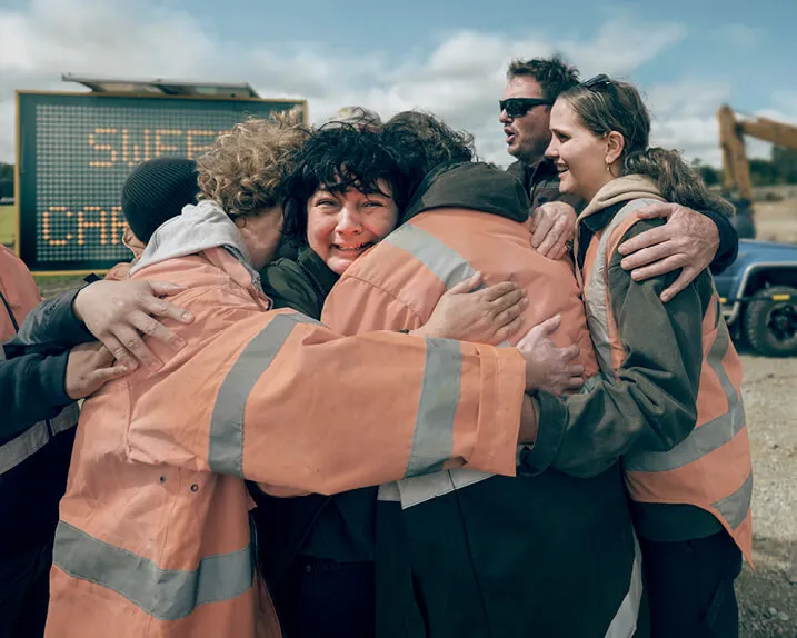 A construction crew share a hug together