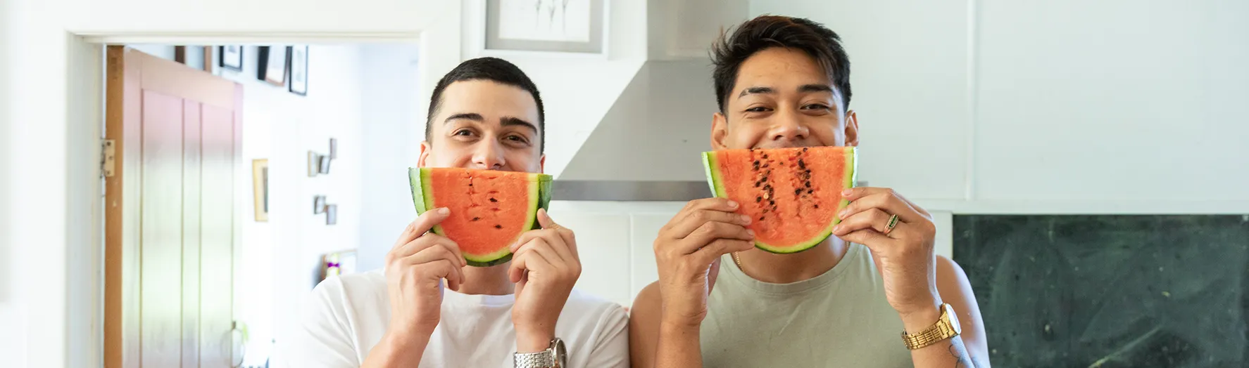 Two friends laughing, holding up watermelon slices